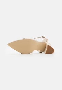 Sandal con tacco alto beige, punta affilata, cinturino alla caviglia, suola testurizzata e tacco a blocco marrone chiaro. Materiale in pelle liscia.