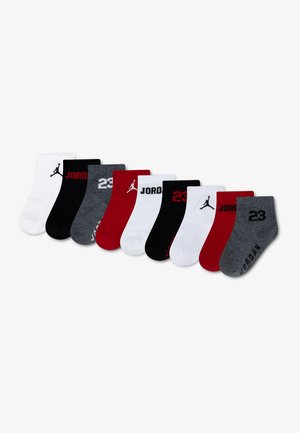 Neuf paires de chaussettes courtes de la marque Jordan en blanc, noir, rouge et gris avec des logos, du texte et des motifs du numéro 23 disposés en rangée.