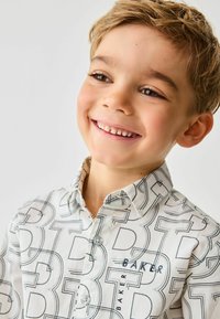 Fehér ing, amelyet merész fekete geometriai minta díszít, gombos gallérral és edzett kék "BAKER" logóval.