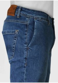 Jeans in denim blu con un lavaggio medio, dotati di un'etichetta in pelle alla vita, tasche laterali e posteriori, e dettagli cuciti lungo le cuciture.