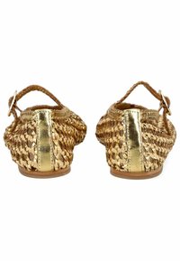 Zapatos planos de oro y beige tejidos con una correa trasera, que presentan un acento metálico en el tacón y un diseño abierto y transpirable.