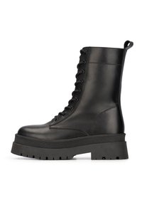 Bottines noires en cuir avec une semelle épaisse, un design à lacets et une languette au talon. Fini mat avec des motifs texturés.