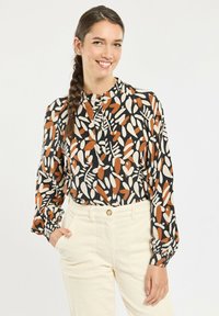 Long-sleeve blouse with a black background, featuring an orange and cream leaf print. Round neckline with button detail and gathered cuffs.