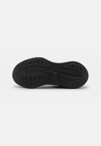 Suola di scarpa in gomma nera con un motivo testurizzato caratterizzato da scanalature e creste per una migliore trazione. Design leggero con una finitura liscia.