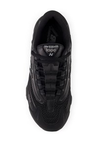 Mustad musta New Balance 1000 treeningjalats, millel on kohev pealmine osa, polsterdatud kaelus ja mitmed tekstuurid. Includeerib silmapaistvat logo ja triibulisi aktsente.