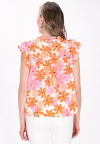 Bluse mit Blumenmuster in Orange, Pink und Beige auf weißem Hintergrund. Rüschensleeves und ein Schlüsselloch-Detail im Rücken. Leichter Stoff.