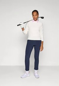 Valge soonikkoega kampsun, roosa kraega särk, mereväe golfipüksid, valged tossud, käes golfikepp, käes kinnas. Lihtne, sportlik riietus.