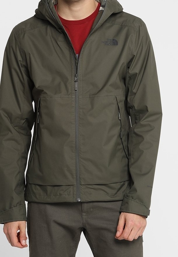 Grøn vandtæt jakke med hætte, fuld lynlås foran og to sidelommer. Har North Face-logoet på venstre bryst.