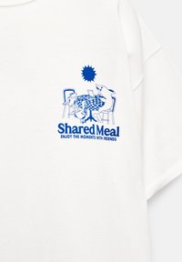 T-shirt blanc à manches courtes avec une illustration graphique bleue d'animaux autour d'une table à carreaux, avec le texte : "Repas partagé, PROFITEZ DES MOMENTS AVEC DES AMIS."