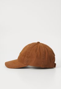 Brown corduroy cap with a curved brim, adjustable strap at the back, and stitched ventilation holes on the top.