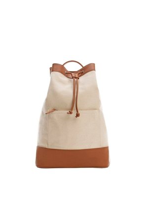 Sac à dos en toile beige avec garniture en cuir marron, fermeture par cordon, poche avant et poignée supérieure sur fond blanc.
