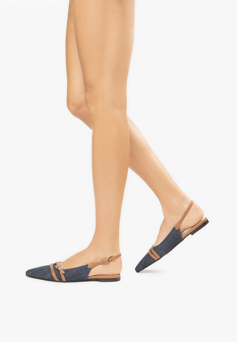 Denim slingback flade har spidse tæer, en læderrem med spænde og en kontrastfarvet brun accent, på en lav, flad sål.