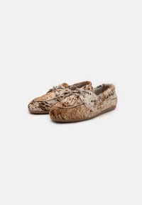 Brown and tan moccasin shoes with a textured, fur-like exterior, featuring laces and a low-profile rubber sole. Spots and patterns present.