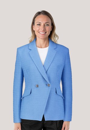 Blue textured blazer with a double-breasted design, notch lapels, and silver buttons. Paired with a white top and black pants.