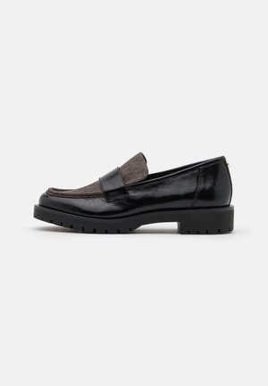 Mocassins en cuir noir avec un accent en daim gris et une semelle en caoutchouc épaisse. Présente des détails de couture et un petit accent en métal doré.