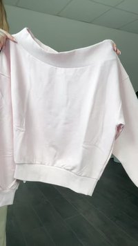 Gaiši rozā džemperis ar ribotu apkakli un aprocēm, kas raksturojas ar brīvu piegriezumu un mīkstu tekstūru. Izceļas ar vienkāršu dizainu bez rakstiem.