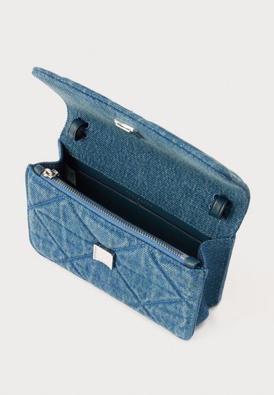 Μικρή μπλε τσάντα από υφασμάτινο καπιτονέ, με ανοιχτό καπάκι, ασφαλισμένη με μαγνητικά κλιπ και εσωτερική θήκη με φερμουάρ.