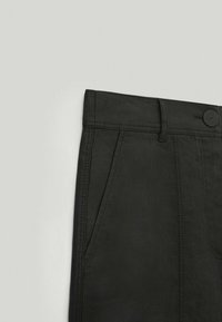 Pantalon en tissu noir avec une finition texturée. Comprend une fermeture à bouton, des passants pour ceinture et des poches latérales. Design structuré et ajusté.