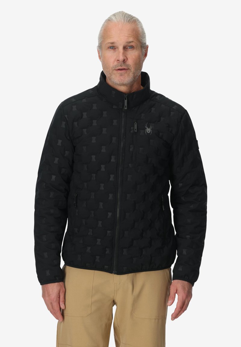 Giacca nera trapuntata con colletto alto e tasche con zip, caratterizzata da un motivo sottile e un logo a forma di ragno sul petto.
