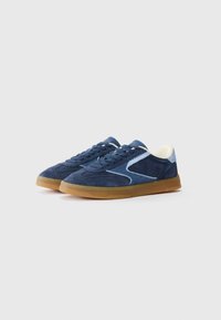 Marineblå ruskinds sneakers med gummisål, med lys blå accent og klassisk snørebåndsdesign. Tekstureret overdel med syede detaljer.