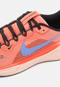 Baskets Nike avec une tige en mesh corail respirant, lacets noirs, un logo swoosh bleu et une semelle en caoutchouc texturée. Comprend un col rembourré.