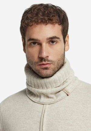 Lys beige strikket turtleneck sweater med ribbet tekstur og en fremtrædende krave. Har et lille stofmærke med teksten "CONERI."