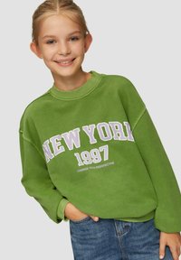 Grüner Sweatshirt mit dem Aufdruck "NEW YORK 1997" in weißem und lila Text, mit lässiger Passform und geripptem Kragen, kombiniert mit blauen Jeans.