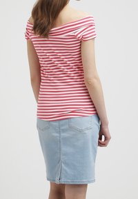 Červené a bílé pruhované top bez ramínek spárovaný se světle modrou džínovou tužkovou sukní s dvěma zadními kapsami a rozparkem uprostřed zad.