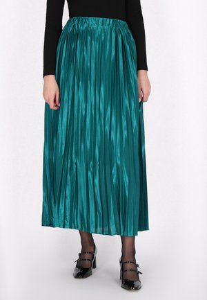 Gonna maxi plissettata color turchese in tessuto satinato con vita elastica. Presenta una superficie liscia e una finitura lucida. Abbinata a scarpe nere.