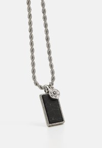 Colar de corrente trançada em prata com um pendente retangular preto de textura rachada e um detalhe floral redondo.