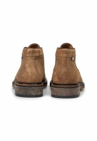 Bruine suède enkellaarsjes met een gladde textuur, ronde neus en een contrasterende donkere rubberen zool. Heeft minimale hardware aan de zijkant.