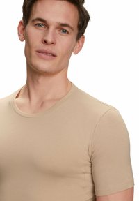Beige T-shirt met korte mouwen, voorzien van een ronde hals, zachte structuur en slim-fit ontwerp, met zichtbare naden langs de zijkanten.