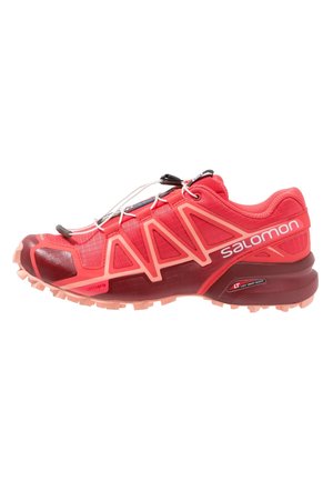 Chaussure de trail Salomon rouge et corail avec semelle robuste, système de laçage rapide et panneau latéral marqué.