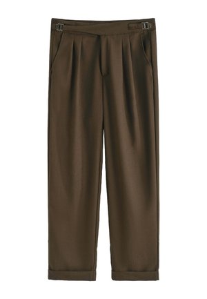 Pantalon plissé marron avec une texture lisse, présente une taille fine et des poches latérales, des jambes fuselées et des ourlets roulés.