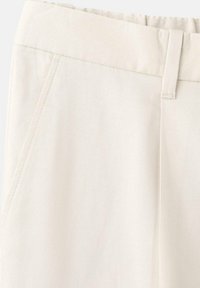Beżowe spodnie wykonane z gładkiego, lekkiego materiału. Posiadają talię o średnim stanie oraz boczne kieszenie ze wzmocnionym szwem.