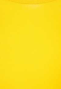 Tela de algodón amarilla con una textura suave, que presenta un diseño simple y un escote redondo, vista en primer plano.
