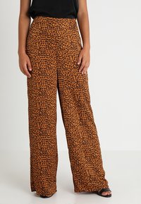 Leveleggs bukser i leopardmønster med en oransje og svart fargepalett. Laget av et mykt stoff med en glatt tekstur.