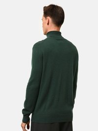 Groene gebreide trui met een hoge kraag, met een gemêleerd afwerking en aansluitende mouwen. Achteraan is er een eenvoudige en minimalistische uitstraling.