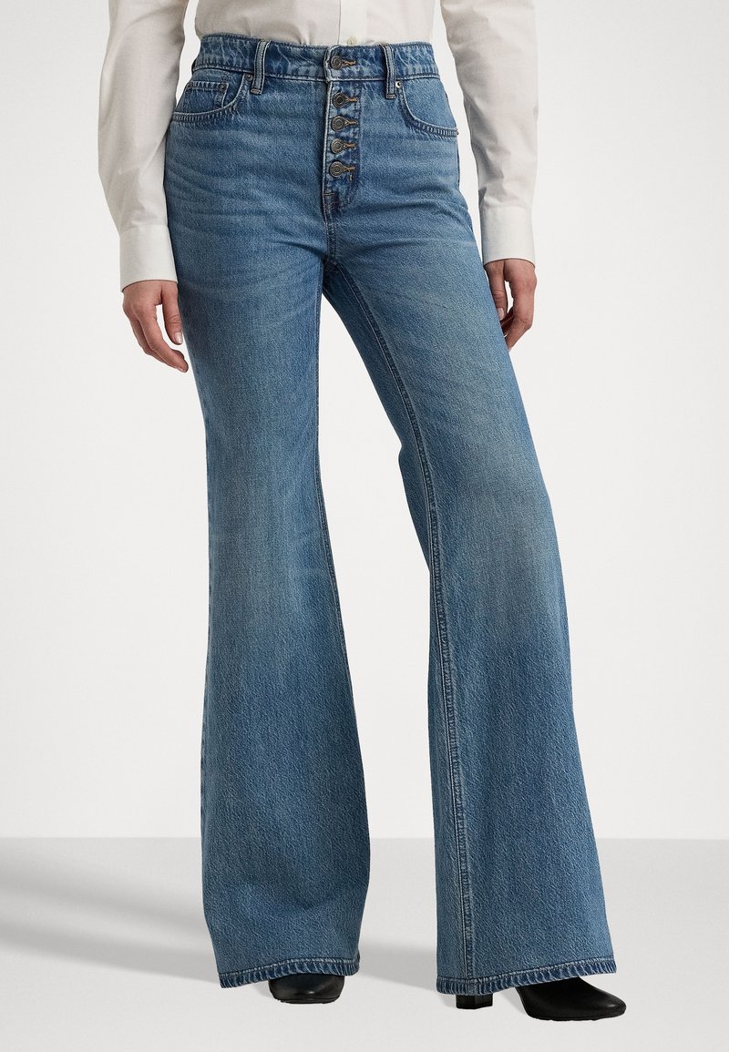 Jean flare taille haute en denim bleu clair, avec une fermeture à cinq boutons, des jambes droites et des coutures visibles le long des coutures.