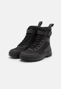 Botas tácticas negras con un upper texturizado, diseño de cordones, correa ajustable, cuello acolchado y una suela gruesa para tracción.