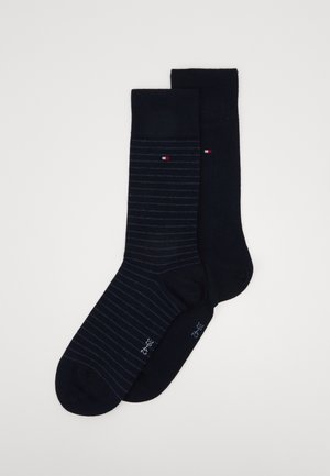 Zwei Paar marineblaue Socken; eines einfarbig, das andere mit feinen Streifen. Beide besitzen ein kleines Logo in Rot und Weiß. Der Stoff sieht weich und elastisch aus.