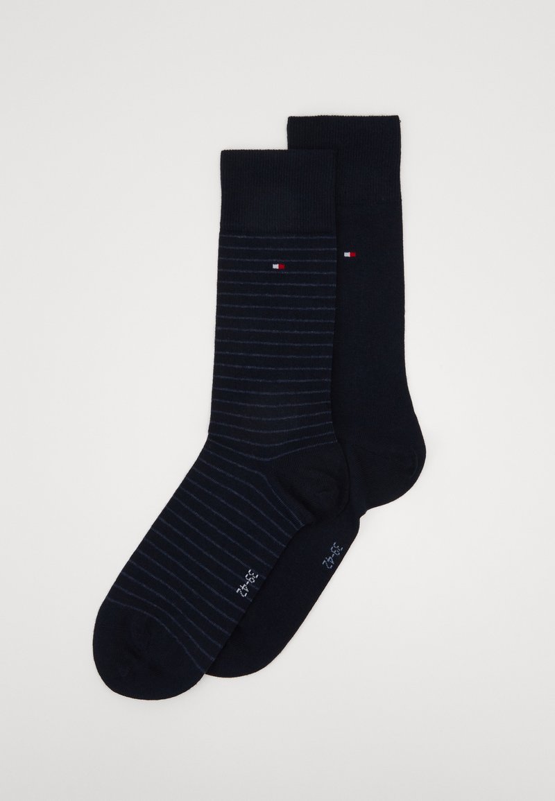 Zwei Paar marineblaue Socken; eines einfarbig, das andere mit feinen Streifen. Beide besitzen ein kleines Logo in Rot und Weiß. Der Stoff sieht weich und elastisch aus.