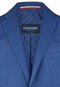 Plavi sako s teksturiranim materijalom. Unutra se nalazi uzorak ponavljajućih logotipa. Oznaka glasi "HECHTER PARIS." Istaknuti kontrast boja s unutrašnjim obodom.