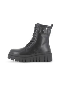 Botas de cuero negro hasta el tobillo con una suela gruesa, con diseño de cordones, acentos metálicos y una correa con logo en la parte superior.