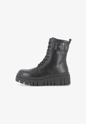 Botas de cuero negro hasta el tobillo con una suela gruesa, con diseño de cordones, acentos metálicos y una correa con logo en la parte superior.