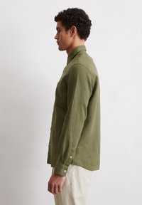 Olive green long-sleeve shirt with a collar, one chest pocket, button-down front, and cuffed sleeves, made of textured fabric.