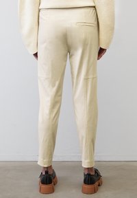 Beiga slim-fit byxor med en mjuk yta, som har en bakficka, sydda detaljer och är kombinerade med svarta skor med tjock sula.
