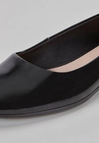 Černé kožené ploché boty s špičatou špičkou, lesklým povrchem a měkkým vnitřním podšitím. Mírně zvýšená podrážka s hladkým povrchem.