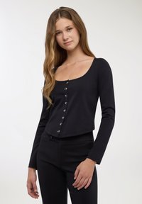 Top nero a maniche lunghe con scollo a barca e chiusura con bottoni sul davanti. Il tessuto è liscio ed elastico, offrendo una silhouette aderente.