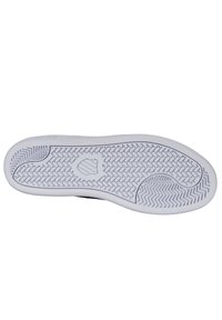 Semelle de sneaker en caoutchouc, blanche avec un motif en chevrons texturé et un emblème en forme de bouclier ; bords lisses et talon arrondi pour la stabilité.